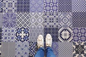 selfie de pies con zapatillas de deporte en el fondo del piso de mosaicos de patrón de arte, vista superior foto