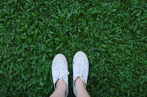 Selfie of feet in sneakers shoes on green grass background with copy space, spring and summer concept photo