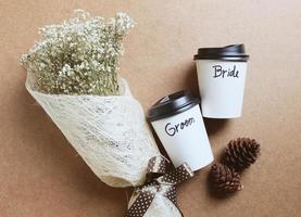 Groom and bride written on coffee cup with bouquet of flower for wedding concept photo
