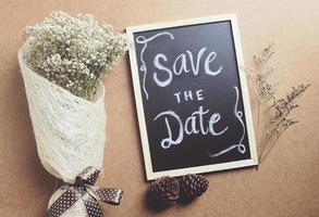 Save the date written on blackboard with bouquet of flower, retro filter effect photo