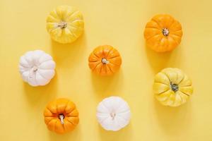 Flat lay style of fresh organic pumpkins on yellow background, halloween and thanksgiving concept