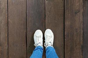 selfie de pies en zapatillas de deporte de moda sobre fondo de suelo de madera, vista superior con espacio de copia foto
