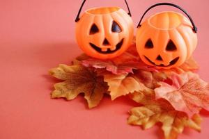 Jack O lantern pumpkins face on autumn leaves with orange background, halloween concept photo