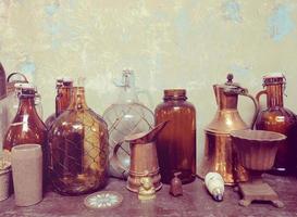 Vintage home decor old brown glass bottles on wooden board with grunge wall, retro home interior photo