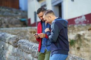 Gay couple looking at their smartphone outdoors photo