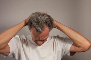 Mature Man 60plus doing back of the neck stretches for back and neck pain photo