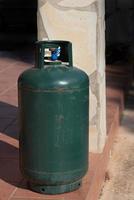 una botella de gas de metal verde se encuentra en una terraza en italia. es una botella de depósito que debe ser rellenada foto