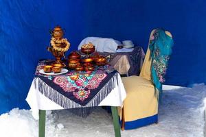 On the table on a colorful tablecloth is a traditional Russian samovar. Russian national tea ceremony photo