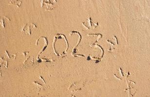 The numbers 2023 are written on the sand on the beach. The concept of the New Year. Happy New Year 2023 background. Travel during the Christmas holidays photo