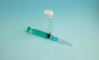 A syringe and a bottle of vaccine stand on a blue background. For the prevention, immunization and treatment of coronavirus infection. The concept of medicine and health care photo