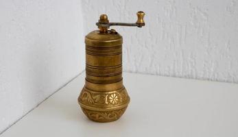 Old bronze bronze coffee grinder stands on a white background photo