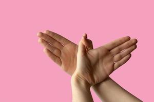 Silhouette of a hand gesture similar to a bird flying on a pink background photo