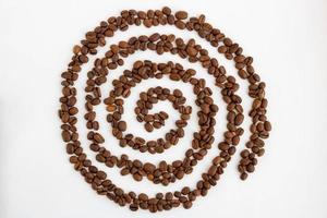 Coffee beans are laid out on a white background in the form of a spiral photo