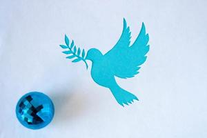 A dove stencil with a twig, cut out of white paper on a blue background for World Peace Day. World Science Day for Peace and Development photo