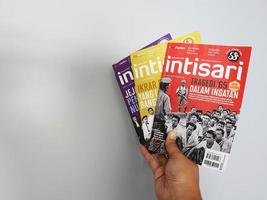 A hand is holding some Intisari magazines photo