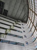 The inside of a tall building, lots of glass and very futuristic. photo