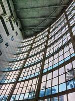 The inside of a tall building, lots of glass and very futuristic. photo