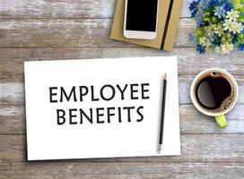 EMPLOYEE BENEFITS text on paper on wooden table with coffee cup and smartphone photo