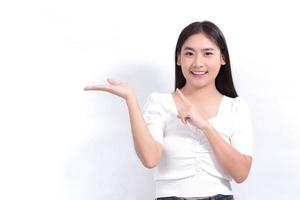 Asian woman in black long hair wears white shirt and shows point up to present something on white background. photo