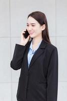 Asian professional business woman wears black suit while calling with customer to sale something. photo