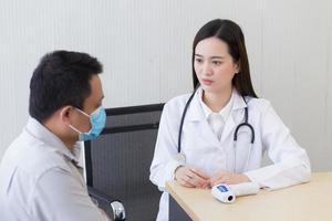 una doctora asiática con una bata blanca de laboratorio da consejos a un paciente foto