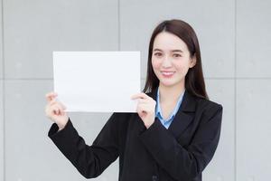 mujer trabajadora de negocios asiáticos sostiene papel blanco para presentar algo. foto