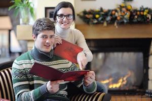 Young romantic couple sitting and relaxing in front of fireplace at home photo