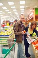 pareja feliz comprando frutas en el hipermercado foto