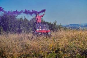 gente emocionada divirtiéndose disfrutando de un hermoso día soleado sosteniendo antorchas coloridas mientras conduce un coche de buggy fuera de la carretera foto