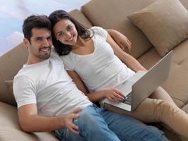 pareja joven relajada trabajando en una computadora portátil en casa foto