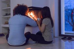 happy multiethnic couple sitting in front of fireplace photo