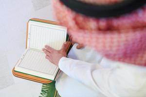 arabian muslim man reading Quran at home photo