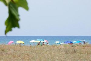 gente tomando el sol bajo las sombrillas en la playa foto