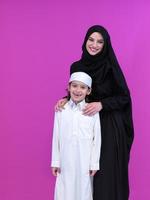 portrait of muslim mother and son on pink background photo