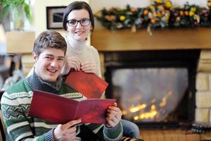 una joven pareja romántica se relaja en el sofá frente a la chimenea en casa foto