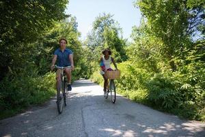 joven pareja multiétnica dando un paseo en bicicleta en la naturaleza foto