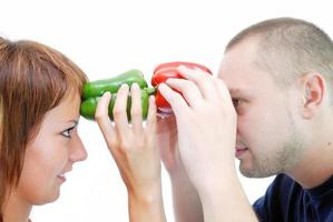 pareja feliz sosteniendo pimientos con la cabeza foto