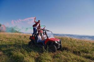 excited people having fun enjoying beautiful sunny day holding colorful torches while driving a off road buggy car photo