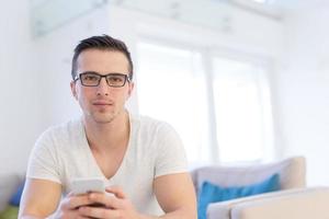 joven usando un teléfono móvil en casa foto