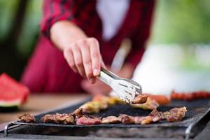 hombre cocinando comida sabrosa en la parrilla de la barbacoa foto