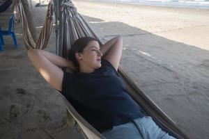 bella joven hispana descansando en una hamaca junto a la playa foto