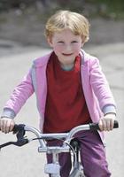 linda niña conduciendo bicicleta en un día soleado foto