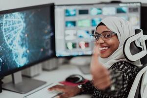 Young Afro-American modern Muslim businesswoman wearing a scarf in a creative bright office workplace with a big screen. photo