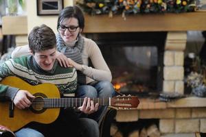 Young romantic couple sitting and relaxing in front of fireplace at home photo