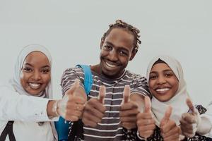 Group portrait of happy African students standing together against a white background and showing ok sign thumbs up girls wearing traditional Sudan Muslim hijab fashion photo