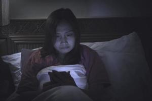 mujer asiática jugando en el teléfono inteligente en la cama por la noche, gente de Tailandia, adicto a las redes sociales foto