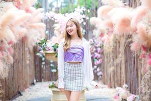 Asian beautiful woman with long bronze hair who wears short skirt and white long sleeve stands in the cafe garden. photo