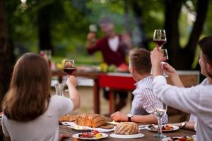 happy friends toasting red wine glass during french dinner party outdoor photo