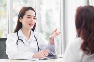 Asian professional  woman doctor suggests healthcare solution to her patient elderly in examination room at hospital. photo