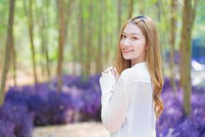 Asian beautiful lady wearing white long shirt smiles happily and stands in the garden as natural theme. photo